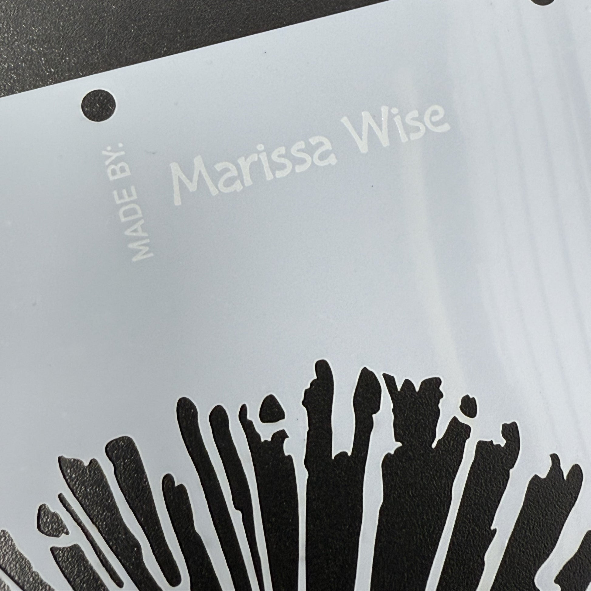 Clear stencil with 'Marissa Wise' branding on a dark surface